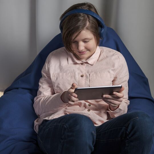Mädchen mit Tablet im Sessel