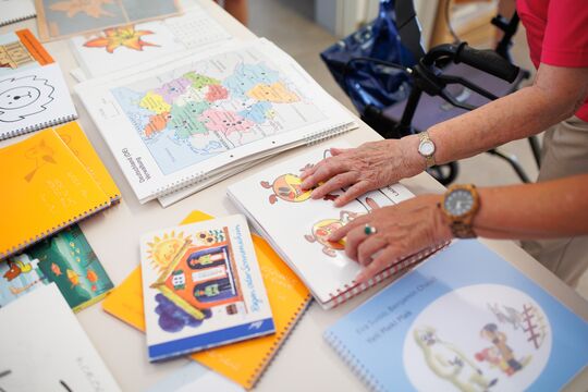 Zwei Hände ertasten taktile Bilderbücher, die auf einem Tisch liegen.