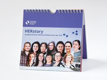 Stehender Kalender mit Brailleschrift, Vorderseite "HERstory - Ausgezeichnete Wissenschaftlerinnen der Technischen Universität Dresden", Foto mit Köpfen der Wissenschaftlerinnen