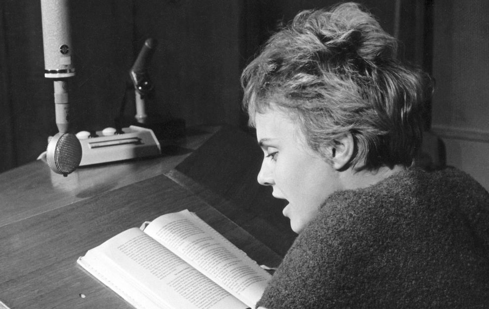 Historisches Foto: Eine Frau am Mikrofon liest ein Buch