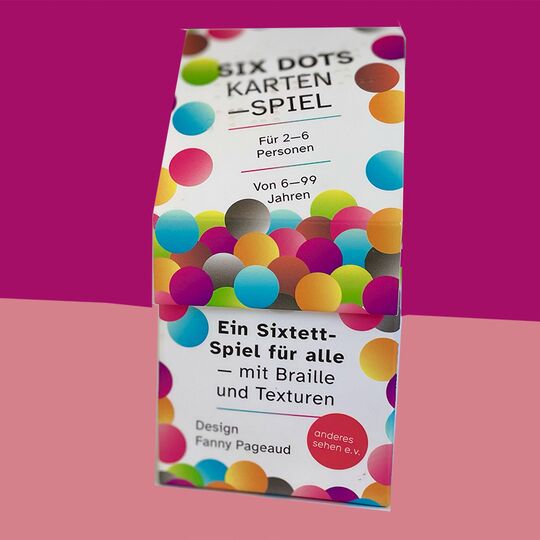 Kartenspiel Six Dots mit farbigen Punkten auf dem Karton, Hintergrund ist oben bordauxrot, unten altrosa