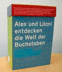 Ein aufklappbarer bunter Karton, Alex und Lilani entdecken die Welt der Buchstaben