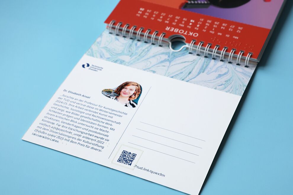 Liegender aufgeklappter Kalender, unterer Teil eine Poskarte mit Text, oben das angeschnittene Kalendarium vom Oktober