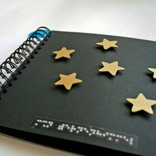Aufgeschlagenes Ringbuch mit aufgeklebten goldenen Sternen auf schwarzer Seite