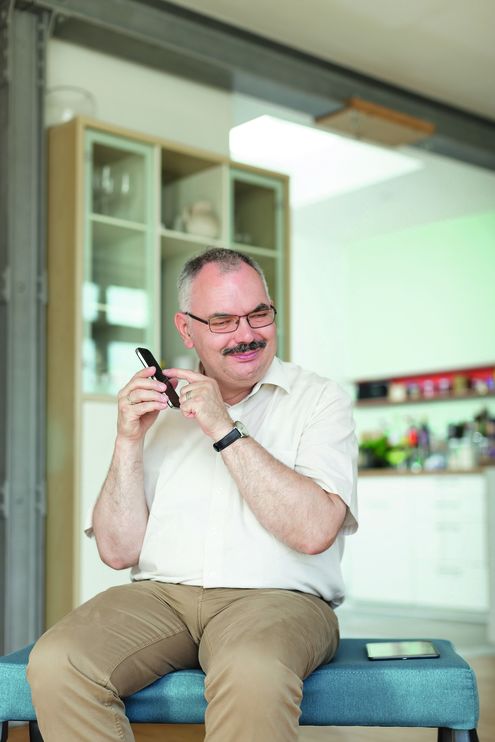 Mann mit Brille sitzt auf Bank und hat ein Smartphon am Ohr