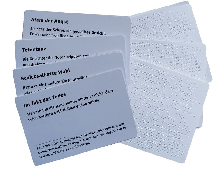 Spielekarten: links mit Text in Großdruck, rechts in Brailleschrift
