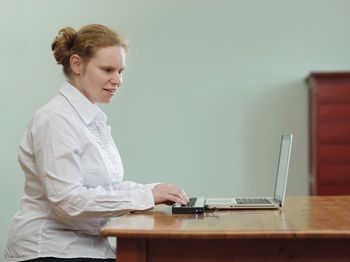 Eine junge Frau mit Braillezeile und Laptop